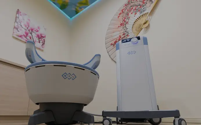 A modern baby high chair positioned next to an air purifier in a room with decorative elements including cherry blossom-themed wall art and a traditional hand fan, designed under the consultancy of a Sexual Health Expert in