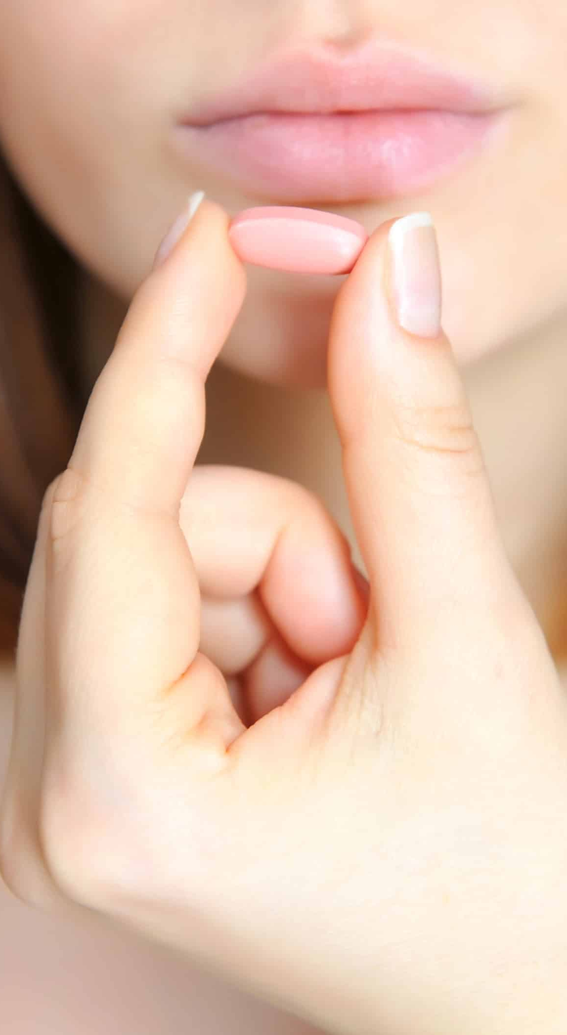 Close-up of a sexual health expert's fingers forming a silent gesture next to their lips.