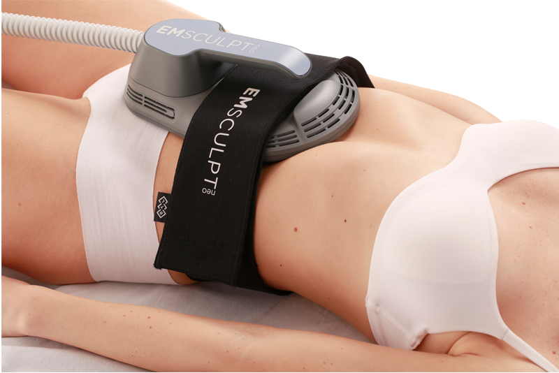 A person undergoing a non-invasive body sculpting treatment with an EmSculpt NEO device applied to their abdomen.