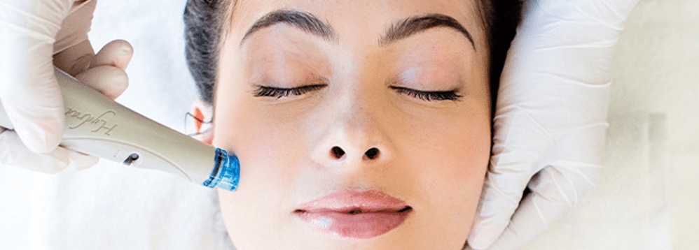 A woman receiving a HydraFacial treatment from her best friend to rejuvenate her skin.