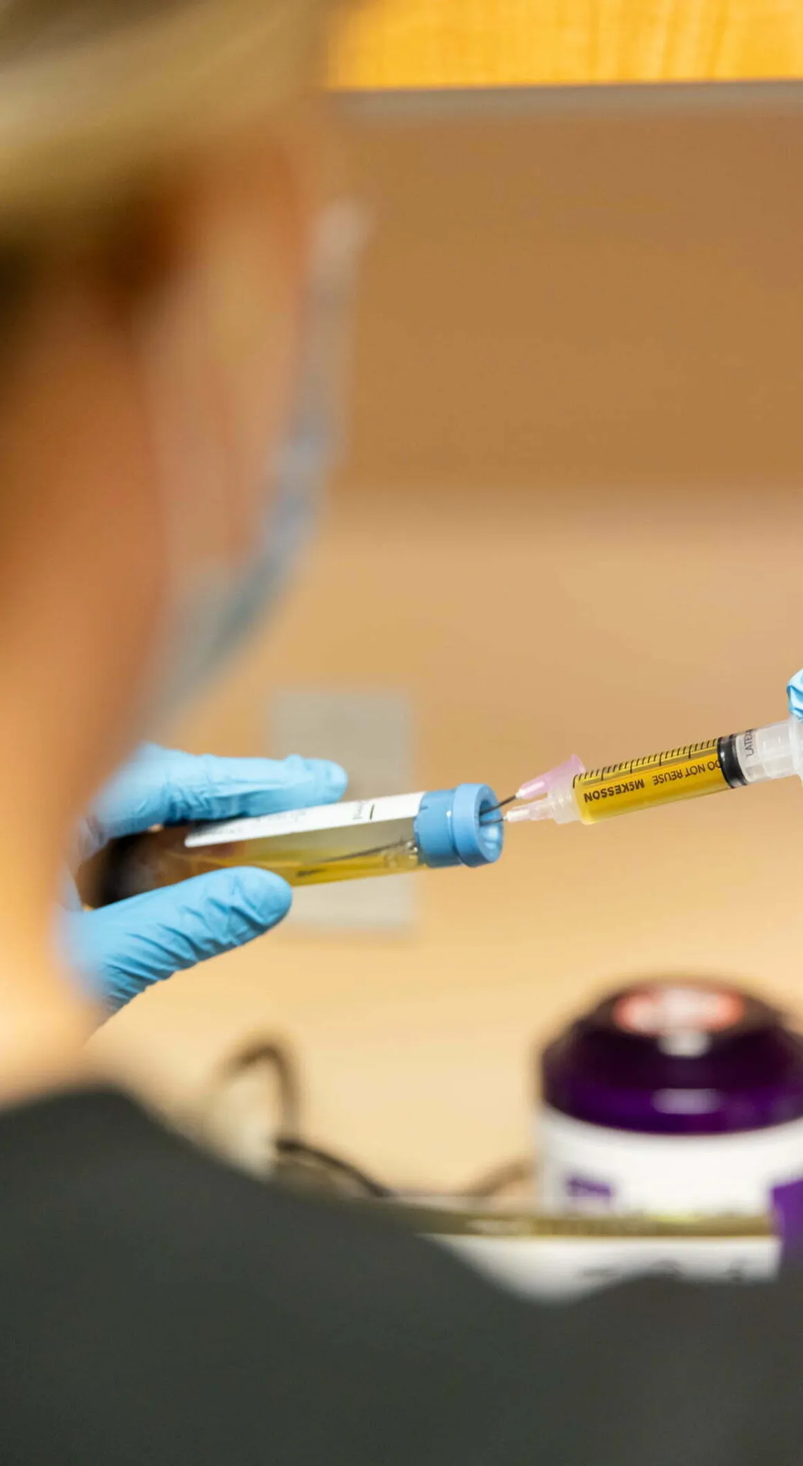 A Sexual Health Expert in Los Angeles, wearing gloves, is preparing a syringe for administration, with a focus on the precise measurement of the vaccine or medication.