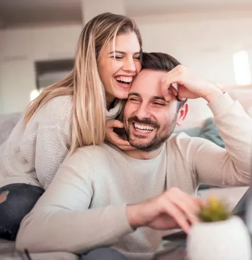A cheerful couple enjoying a playful and affectionate moment together on the couch after consulting with a Sexual Health Expert in Los Angeles.