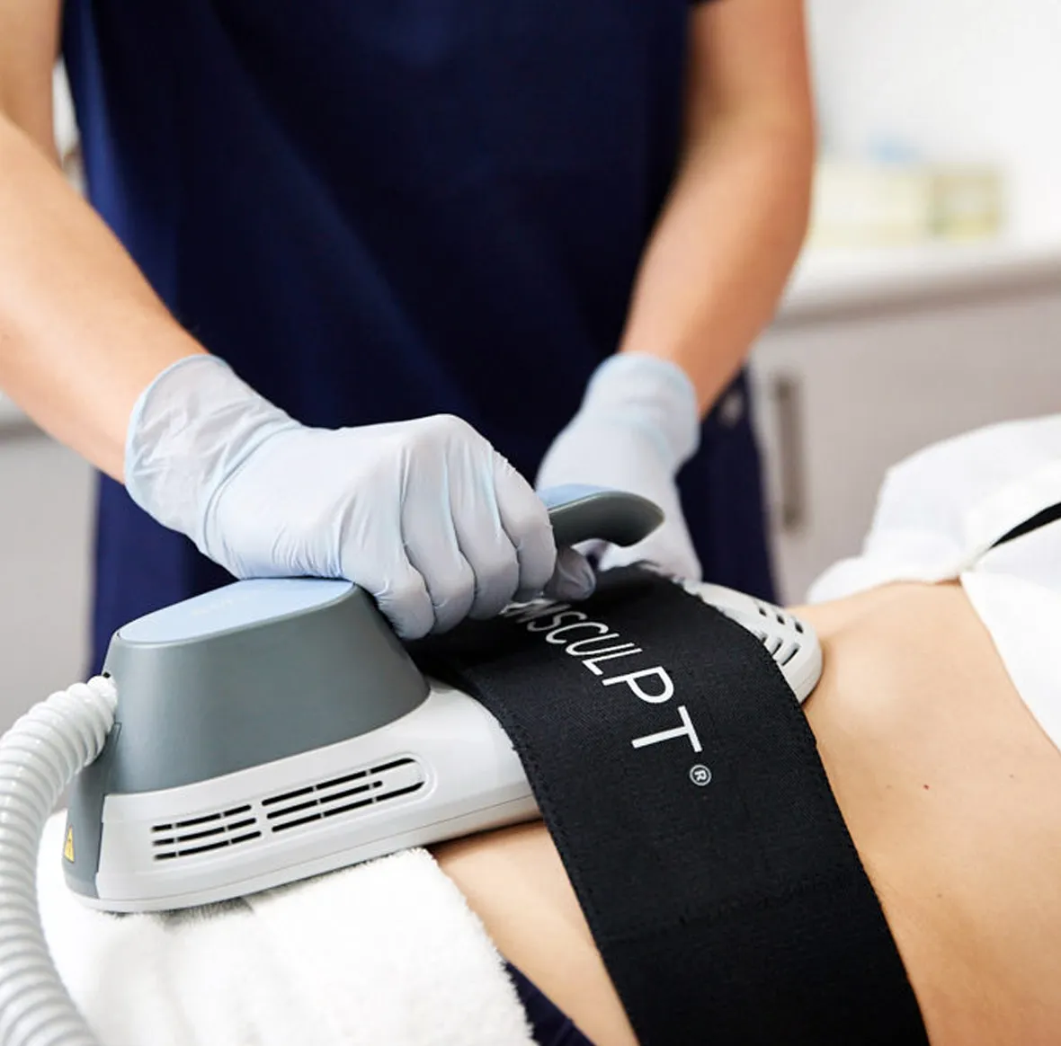 A Sexual Health Expert in Los Angeles is performing a non-invasive body sculpting treatment on a client using a specialized device.