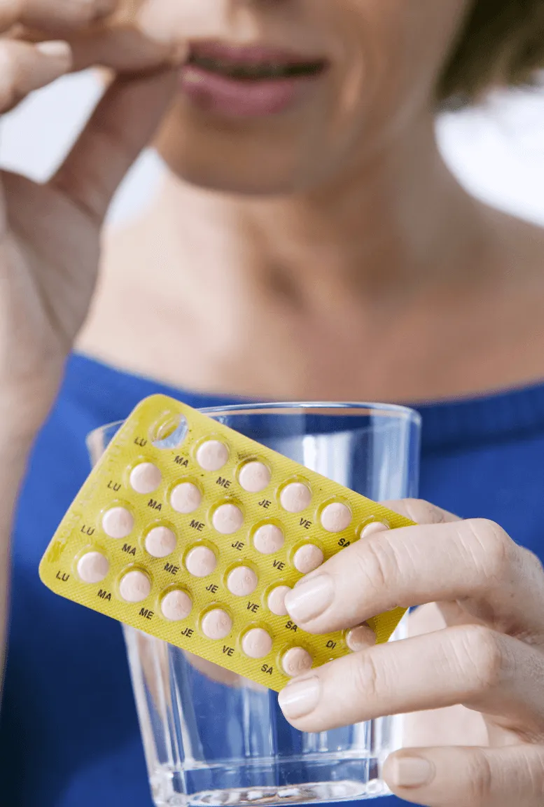 A sexual health expert in Los Angeles holding a blister pack of pills and a glass of water, potentially preparing to take medication.