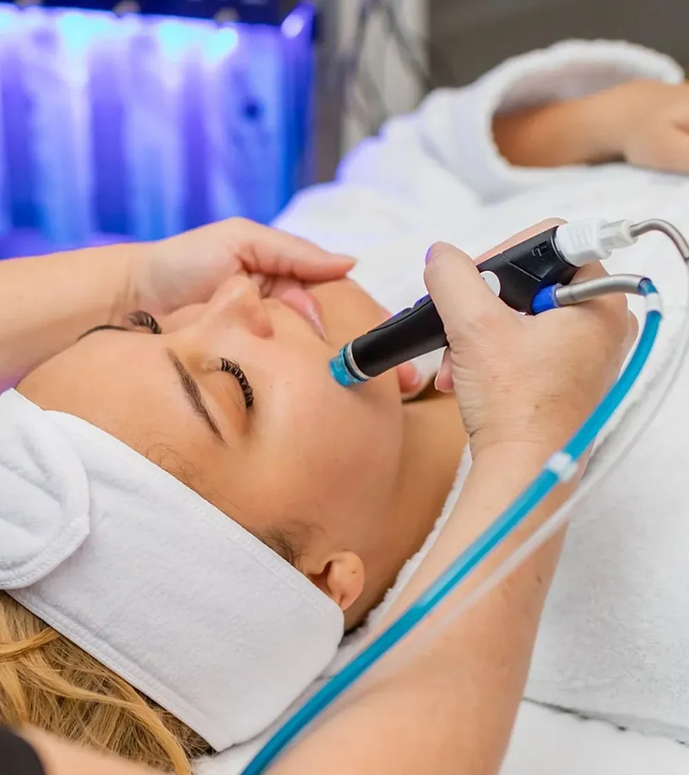 A person receiving a hydrating skin treatment from an expert in sexual health using specialized equipment at a beauty spa.