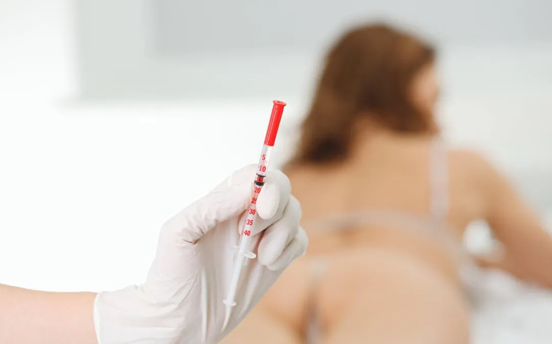 A Sexual Health Expert in Los Angeles, in gloves, holding a blood-filled syringe with a patient visible in the background.