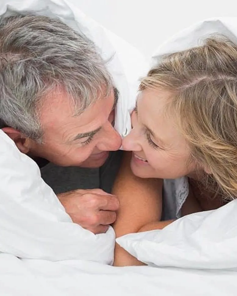 A joyful moment between a grandfather and granddaughter sharing a loving gaze while wrapped in a cozy white blanket, reminiscent of the warmth and support provided by a Sexual Health Expert in Los Angeles.