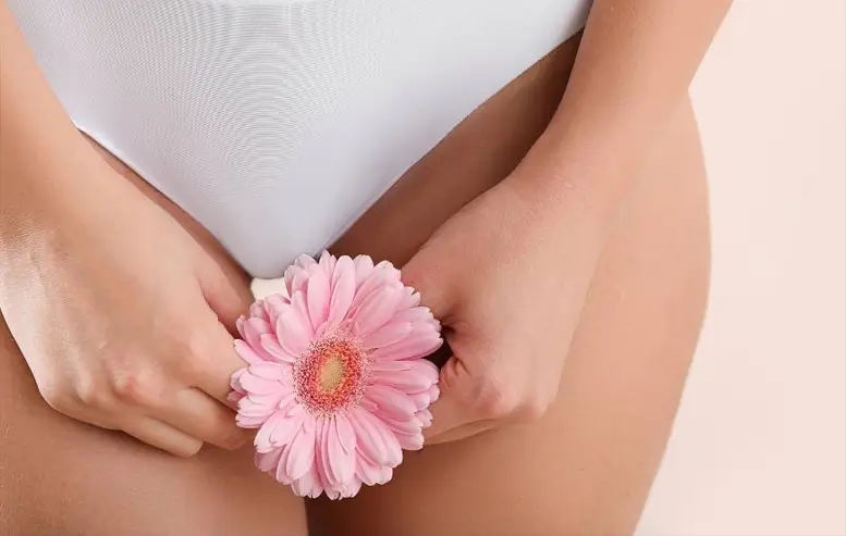 A Sexual Health Expert in Los Angeles holding a pink flower close to their body as a symbol of feminine care and wellness.