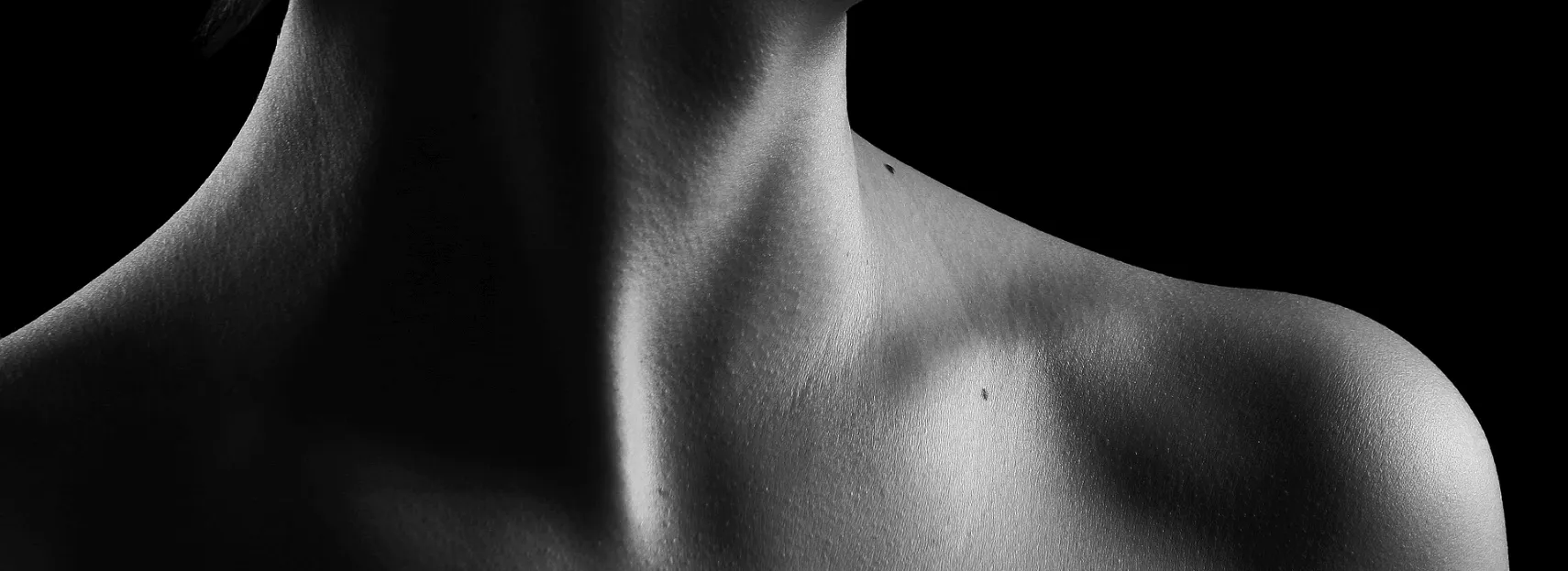 A monochrome side profile of a human neck and shoulder with a play of light and shadow highlighting the contours of the skin, captured by a Sexual Health Expert in Los Angeles.