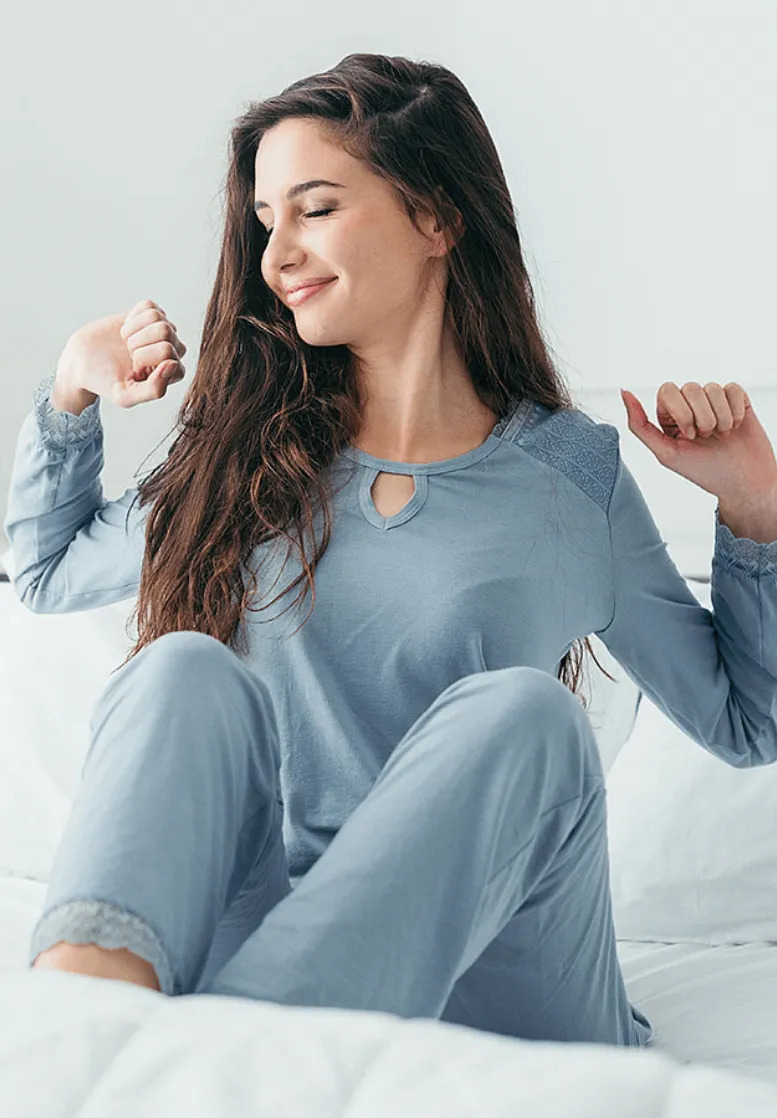 A Sexual Health Expert in Los Angeles, wearing comfortable casual clothes, stretching with a content smile, sitting on a bed with a bright white background.
